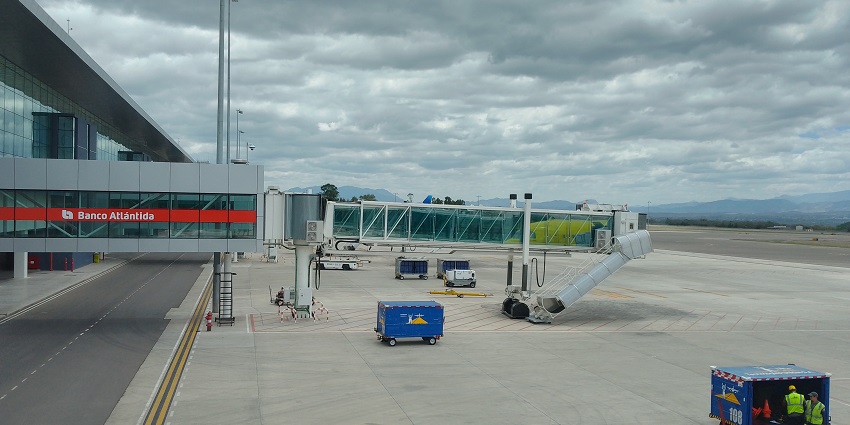 Palmerola International Airport operating with ground crew working near the jet bridge