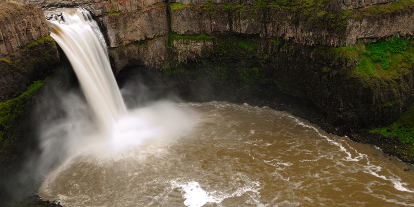 A dramatic waterfall plunging into a deep basalt canyon in Washington State.