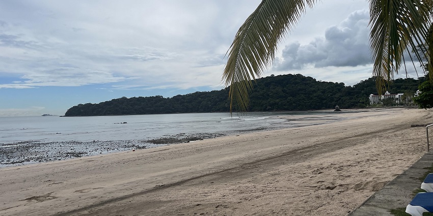 A picture of a stunning beach with golden sand and tranquil waters, with an island in the background