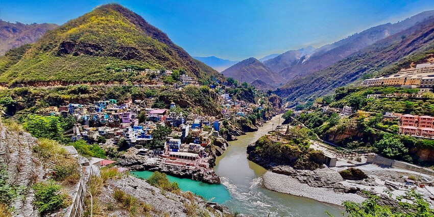 Two rivers, Alaknanda and Bhagirathi, meet at Devprayag, Uttarakhand, surrounded by hills.