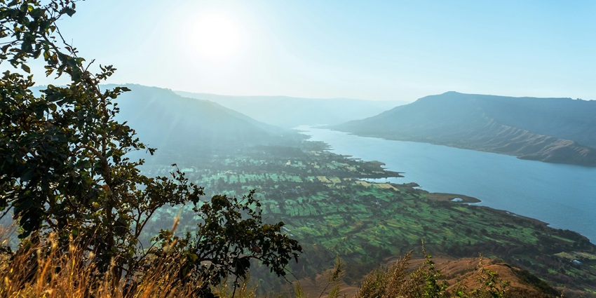 An image of green terraced slopes enveloped in mist, showcasing Panchgani, one of the most beautiful hill stations in India in July.