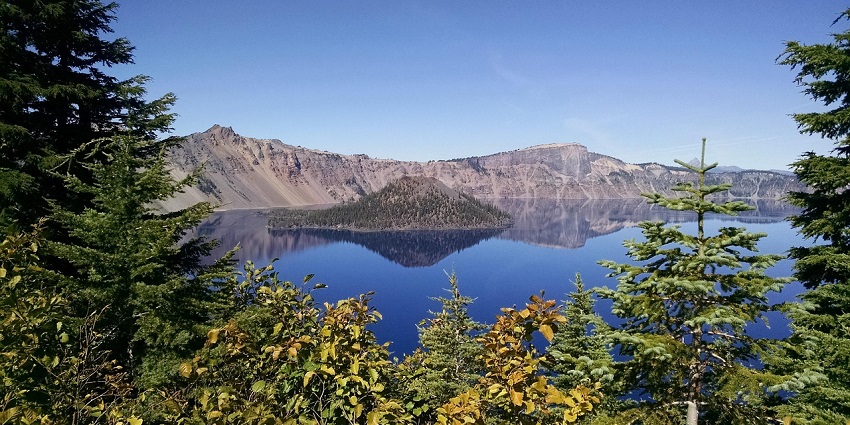 A picturesque lake reflecting majestic mountains and dramatic clouds under a vibrant sky.