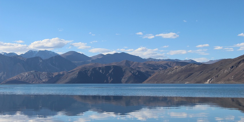 Pangong Tso Lake with perfect reflection of sandy shores and distant sandy mountains