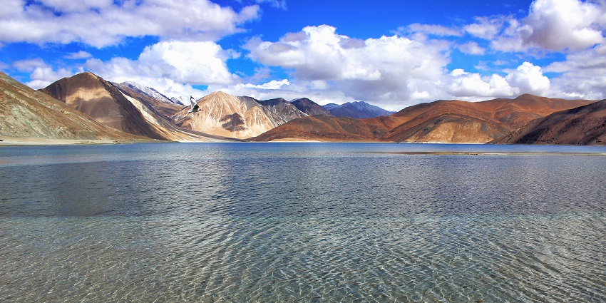 A picture of turquoise waters of the Pangong Tso lake, surrounded by majestic Himalayan mountains