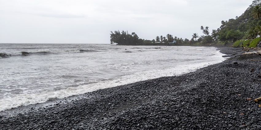 Pebble-filled shore of the Papenoo Beach, one of the black sand beaches in the world.