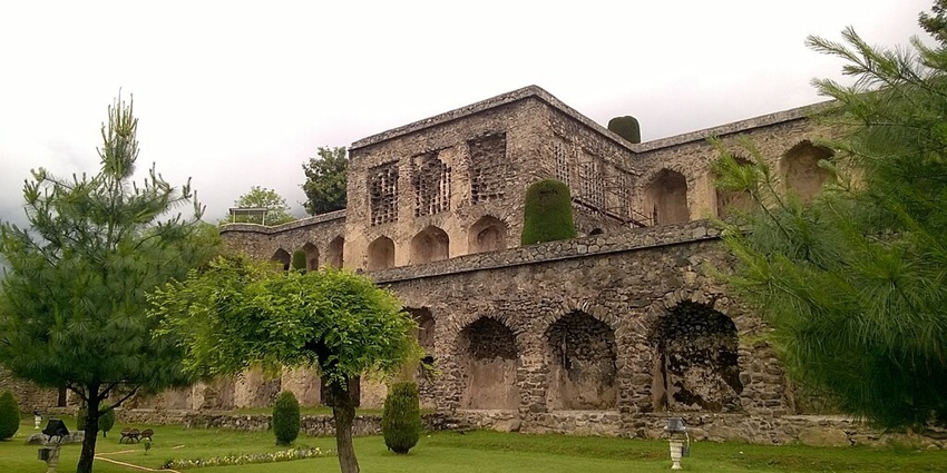 Pari mahal with old architecture, green grass, finely cut trees and lights outside