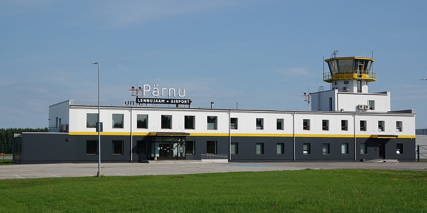 Pärnu Airport building with a lush green grass field in the foreground on a sunny day