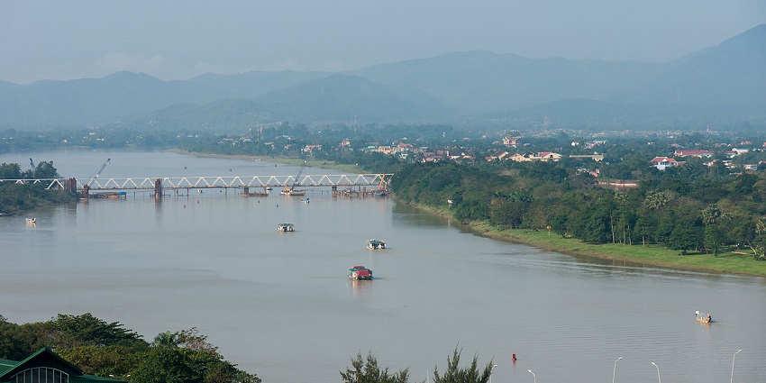 An image of the Perfume River in Hue, Vietnam, with calm waters and a scenic, lush green backdrop