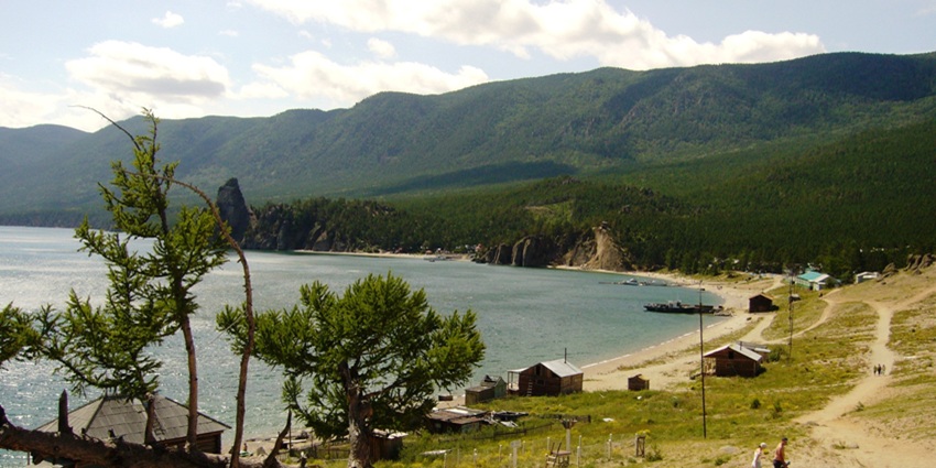 Peschanaya bay with sandy shoreline and small houses near the deepest lake in Russia.