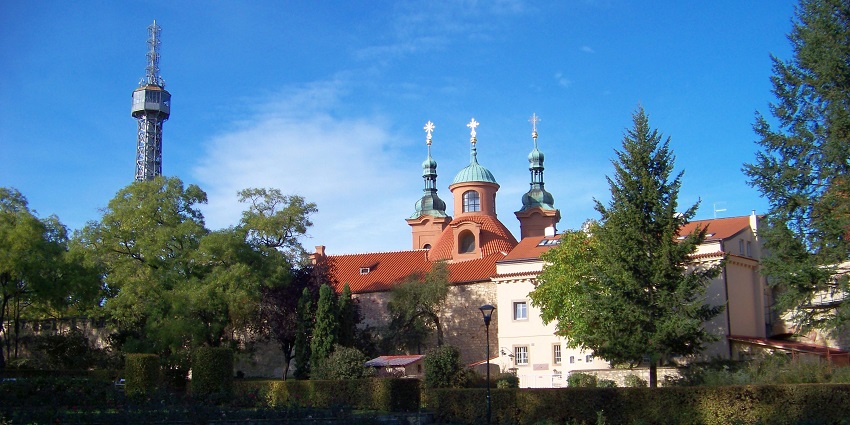 The Petřín Tower is rising above lush trees, offering panoramic views of Prague’s skyline