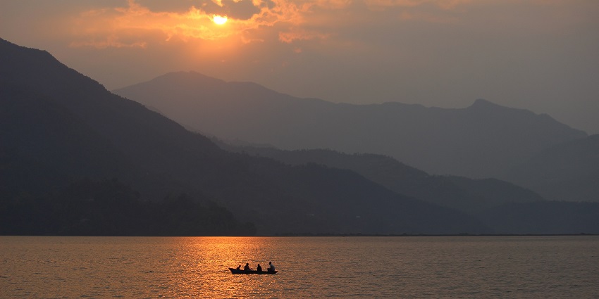 A stunning sunset over Phewa Lake in Pokhara, with golden hues reflecting on the water