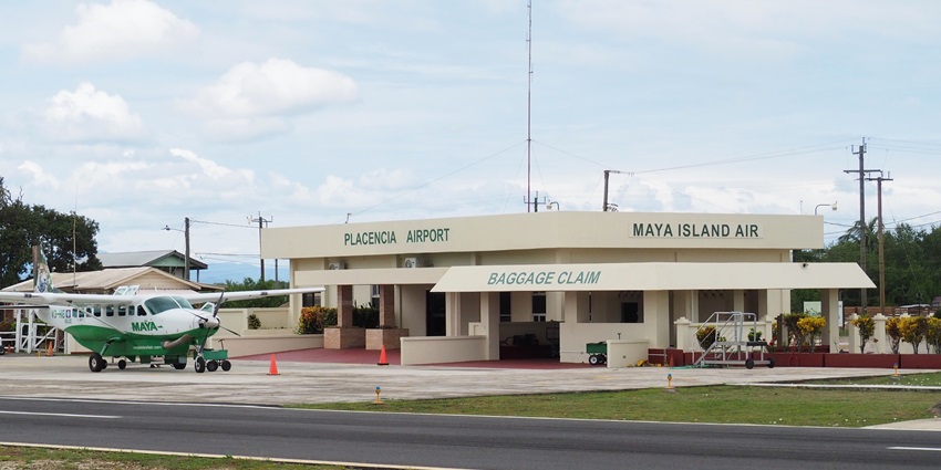 Placencia airport with a green and white propeller aircraft on the runway of the airport