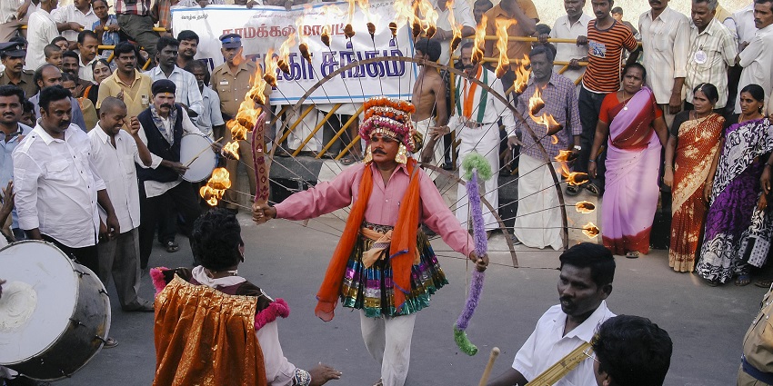 An image of a street with a man dancing with fire rope, illuminating a festive atmosphere during Pongal.