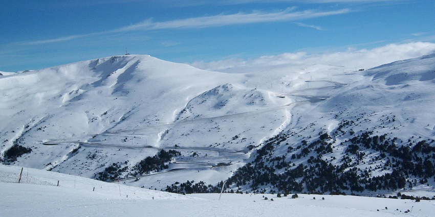 Snow is covering the vast mountain slopes while clouds are drifting across the sky