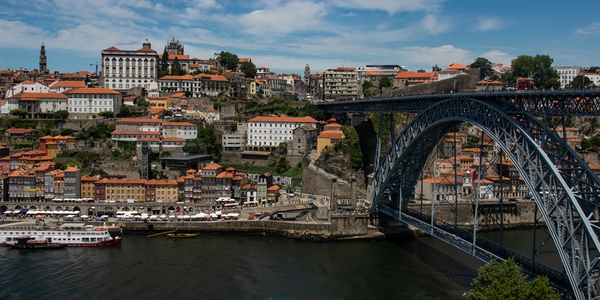 The black-hued Porto Bridge over a water body in Porto, Portugal connects cities