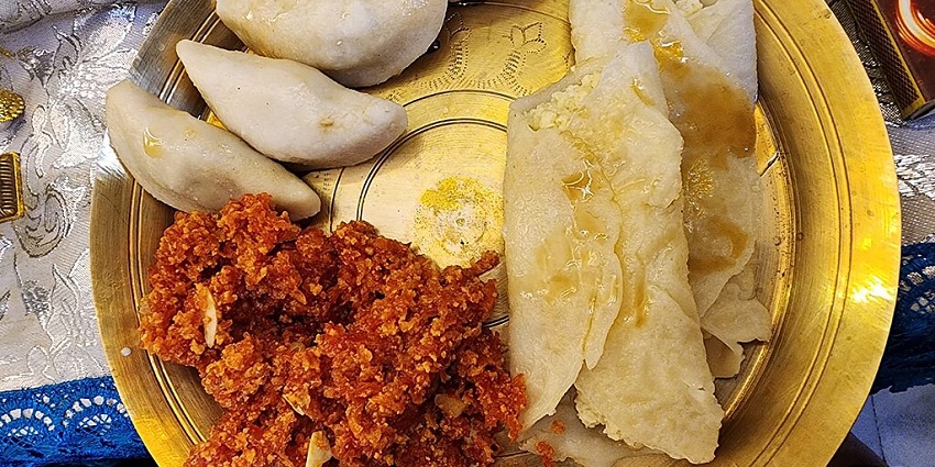 An image of a brass plate filled with traditional Indian sweets malpua, and carrot halwa for the Poush Parbon festival