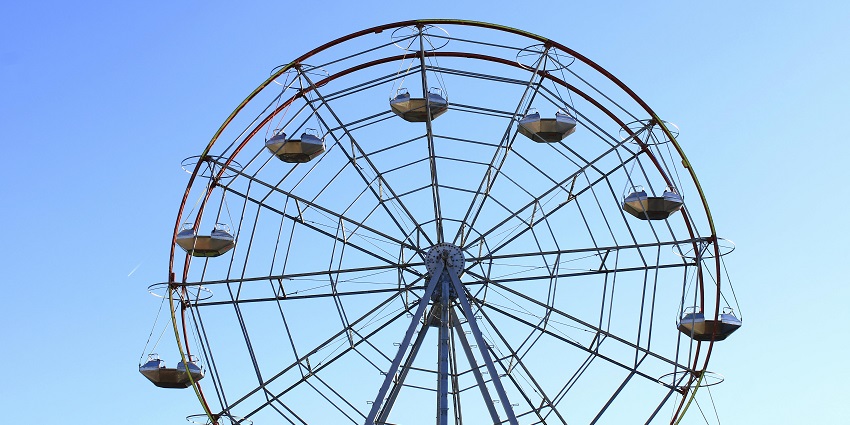 A brightly lit Ferris wheel at an amusement park, surrounded by colorful attractions