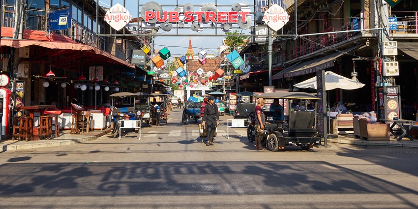 An image of Siem Reap Pub Street in Cambodia with bright signs, restaurants, and people.