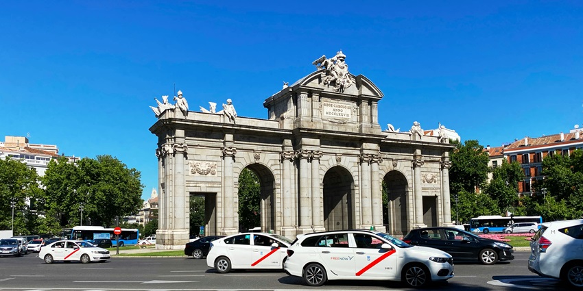 Cars are passing in front of Puerta de Alcalá in Madrid on a sunny and clear day