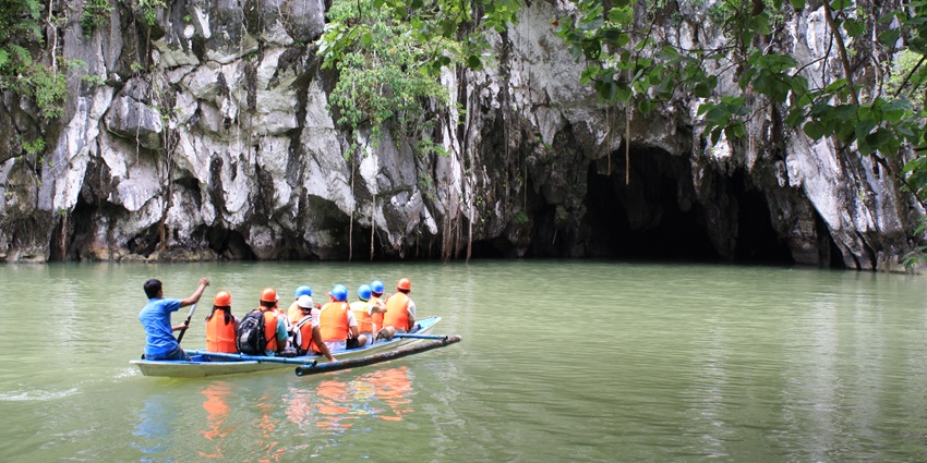 A boat glides through the Puerto Princesa Underground River, surrounded by limestone caves.