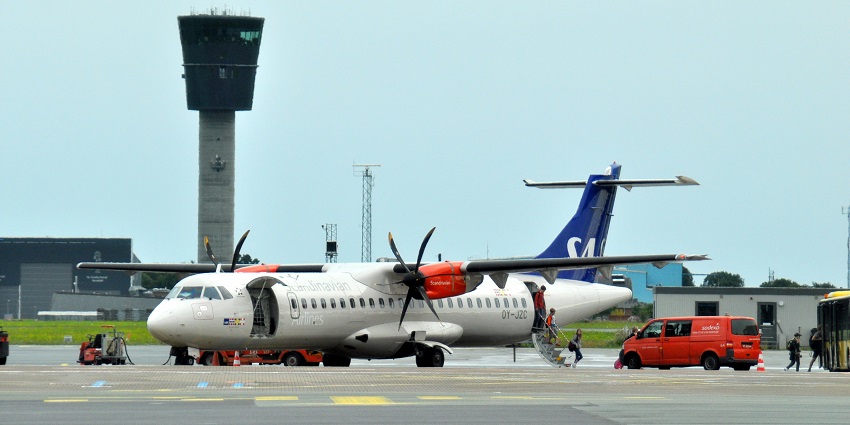 Passengers are boarding the airlines while the ground staff assists them busily.