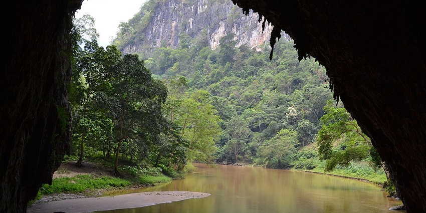 A captivating view inside Puong Cave, with limestone formations and a river flowing through