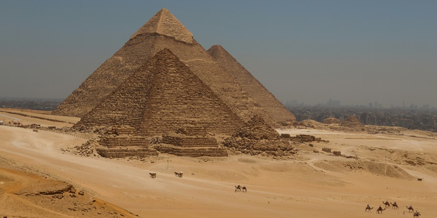 The Pyramids of Giza under a clear sky with desert sand in the foreground