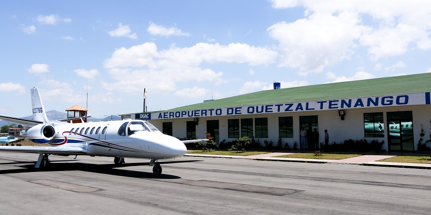 Quetzaltenango International Airport with multiple planes parked and passengers walking.