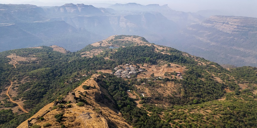 A scenic view of Rajmachi Fort, surrounded by lush green hills, a famous site in India.