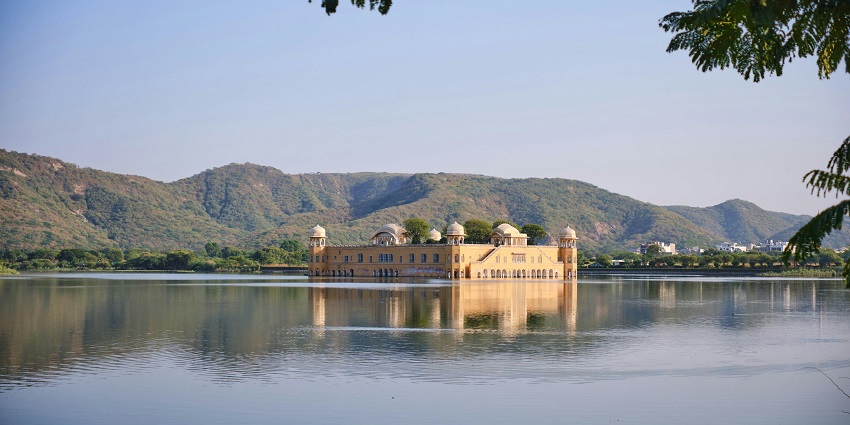 An image of Ramgarh Lake, a lake in Jaipur, with a vast dry basin and surrounding green hills
