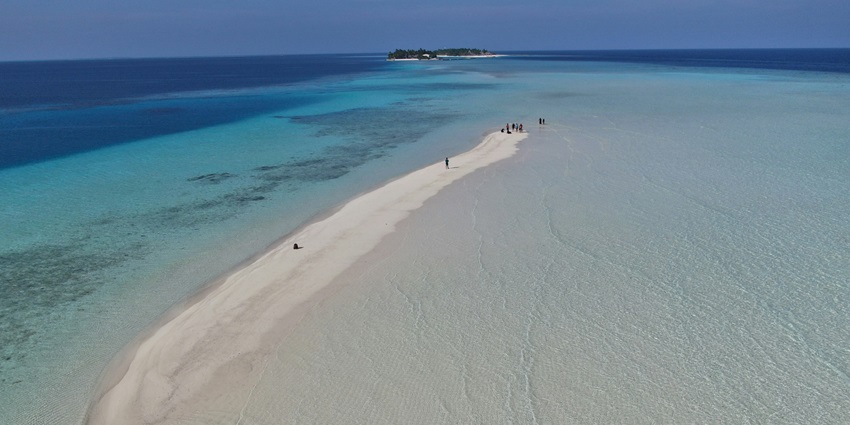 A serene view of Rasfannu Beach featuring clear turquoise water and golden shores.