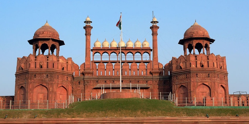 Wide angle view of the Red fort, with the Indian flag flapping at its peak and clear blue sky in the background