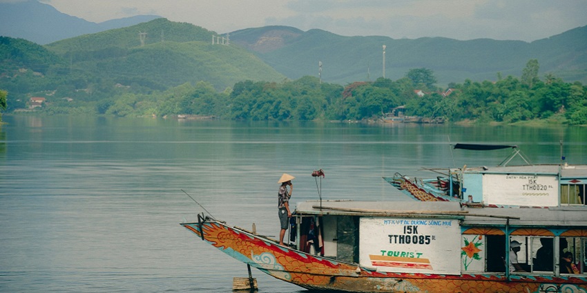 An image of the Red River in Vietnam with calm waters, boats, and a scenic riverside view