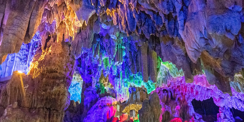 The Reed Flute Cave glows with vibrant colours, illuminating stunning rock formations.