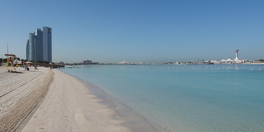 Sunseekers enjoy the pristine sands and turquoise waters at Corniche Beach, a popular waterfront spot, one of the best things to see with family in abu dhabi.