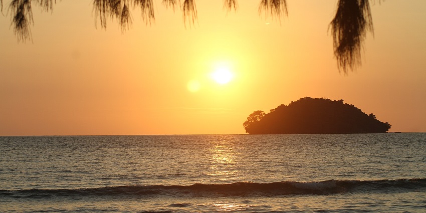 A serene sunset over the ocean, at the Otres Beach in Cambodia, with an island in the back