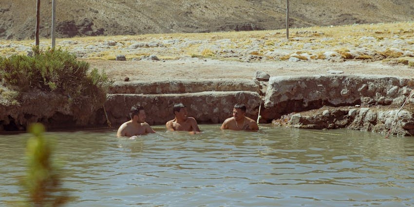 People in an outdoor pool, enjoying the snowy mountain views.