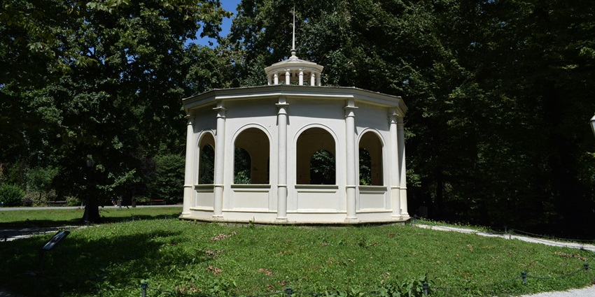 A restored pavilion nestled amidst a garden offers peaceful respite and classic design.