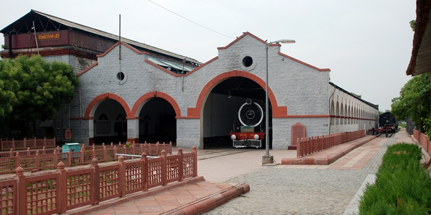A black steam engine at the Rewari Steam Loco Shed, with smoke coming from its chimney