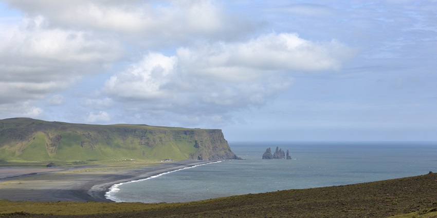 A dramatic black sand beach with towering basalt columns and roaring waves