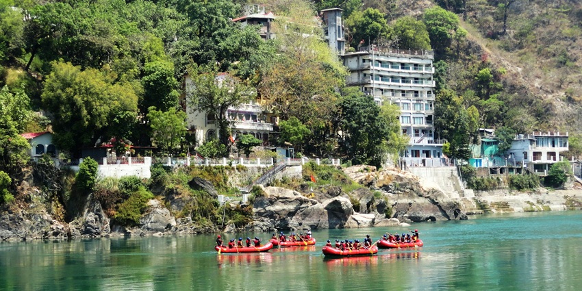 A scenic view of people rafting on the shimmering blue waters of Rishikesh, Uttarakhand.