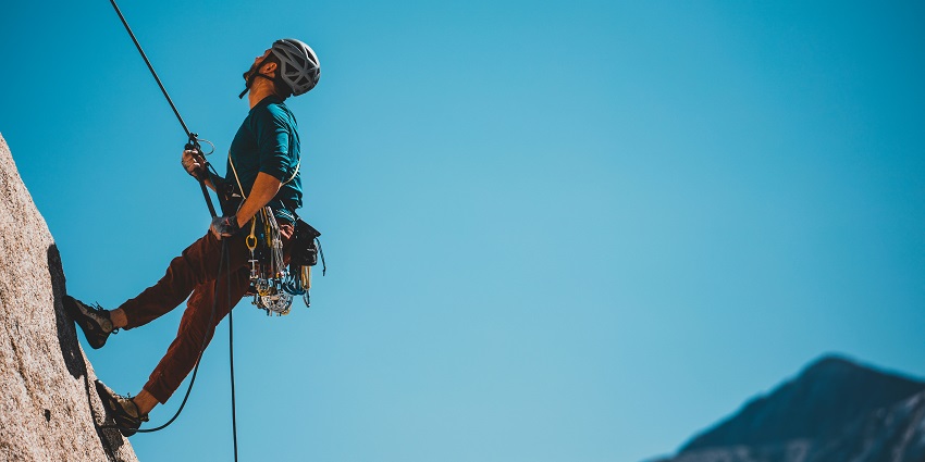 View of a man rock climbing, attached with a cable, one of the thrilling adventure sports