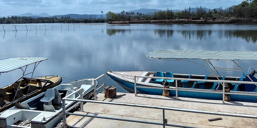 A scenic view of the glistening blue Sal Backwaters with boats on the coastline.