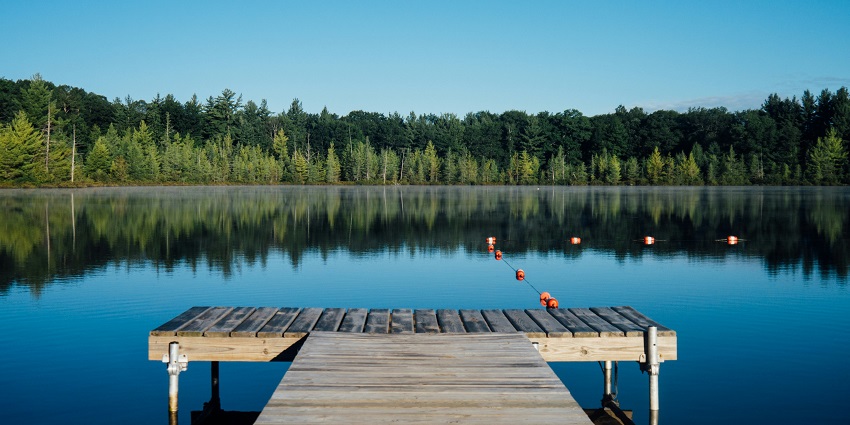 Sangetsar Lake with clear waters, rocky terrain, and submerged tree trunks in the lake