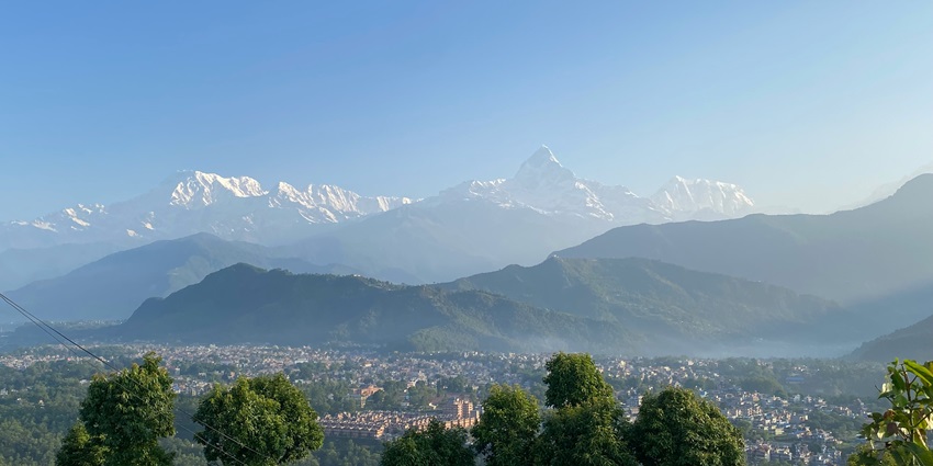 Sarangkot viewpoint with a narrow river flowing and distant snowy mountain peaks
