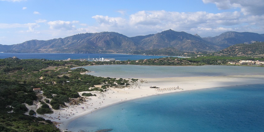 An image of people enjoying at the Sardinia Bay beach with ocean water and distant mountains.