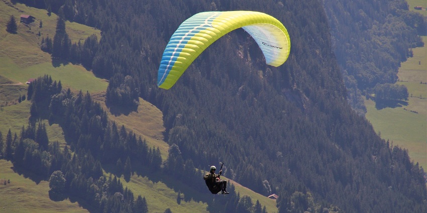 A paraglider in Satpura, with a blue and yellow canopy, enjoying paragliding in India.