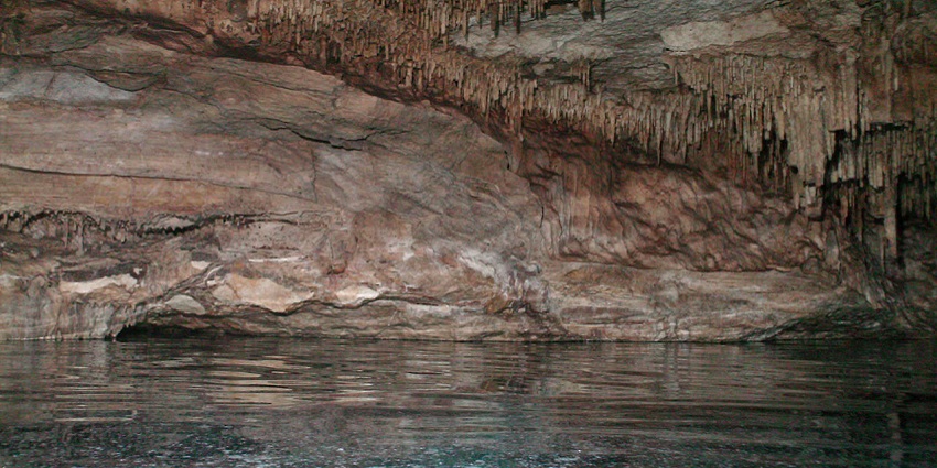 Soft light filters through the dark depths of Sawanworanayok Cave, revealing its rocky walls.