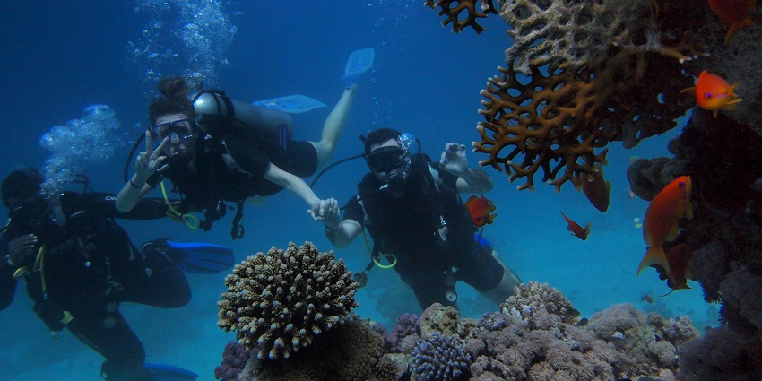 An image of three scuba divers holding hands, one of the Water sports in Agonda Beach.