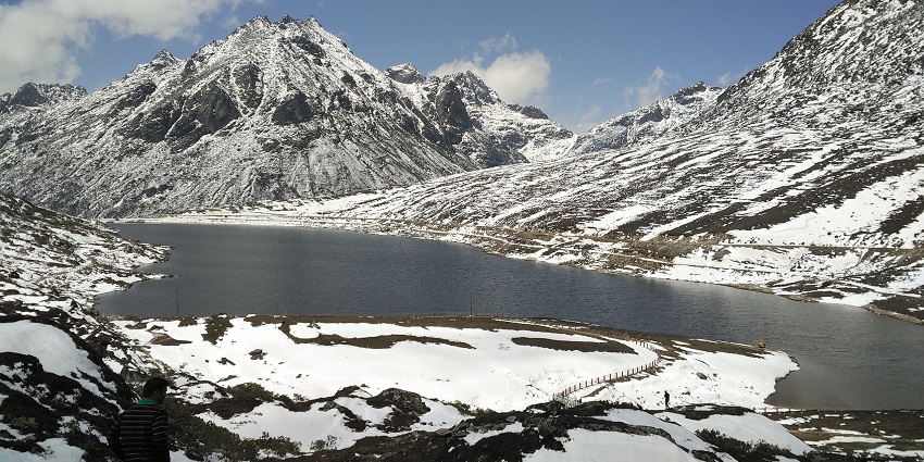 Sela Lake’s frozen surface glistens amid rocky, snow-dusted terrain with dramatic views.